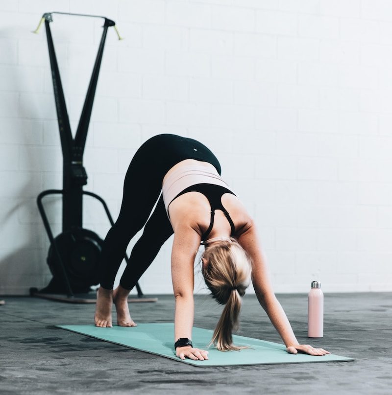 woman in black sports bra and blue denim jeans doing yoga